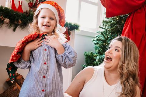 Criança dando gargalhada ao lado da mãe, ambas sorrindo'