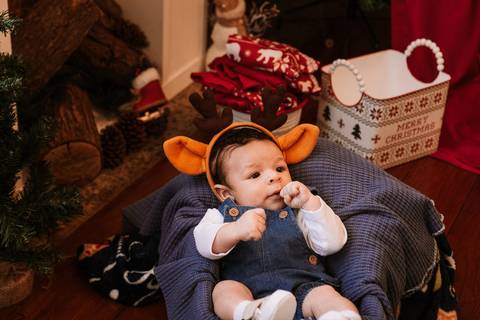 Bebê deitado em mini poltrona com fantasia natalina'