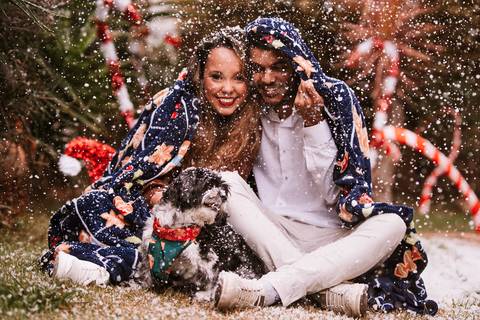 Casal com o cão envolto em luzes de Natal no estúdio.'