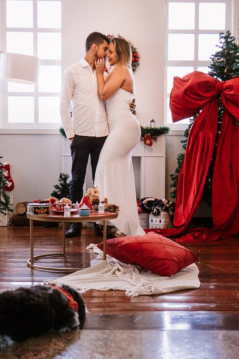Detalhe de pessoa em pé ao lado da mesa de Natal e cortina vermelha.'