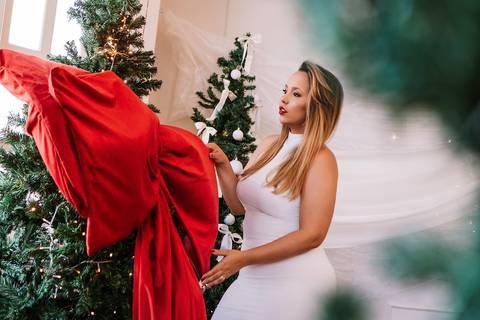 Retrato com tecido vermelho próximo à árvore de Natal.'