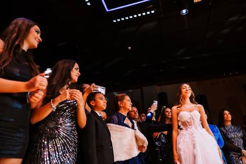 Entrada da debutante emocionada na pista com convidados ao redor'