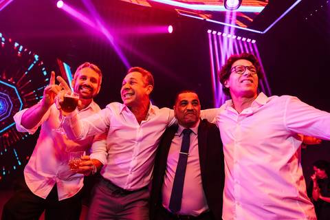 Convidados celebrando na pista com iluminação colorida'