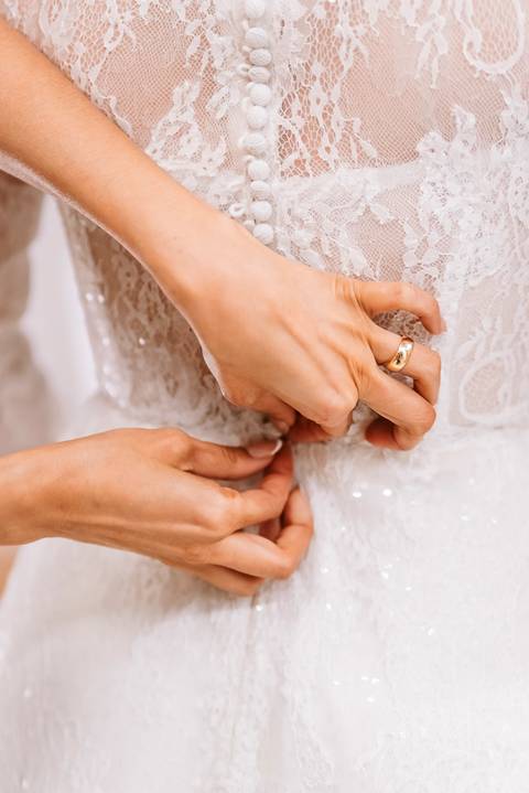 noivo fechando vestido de casamento'