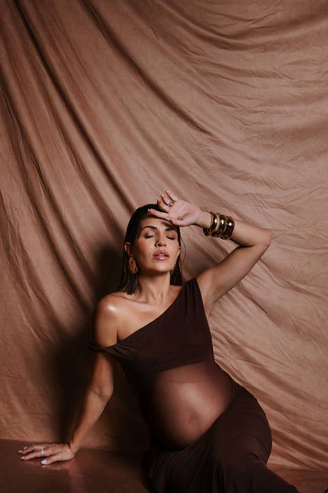     Gestante sentada em pose delicada com estética contemporânea'
