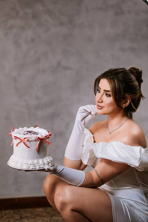     Mulher em ensaio feminino olhando para o bolo de aniversário'