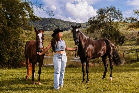     Mulher ao lado de seus cavalos durante ensaio fotográfico no rancho'