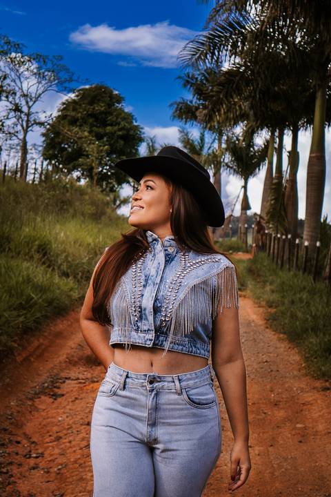     Retrato feminino ao ar livre com chapéu em ambiente rural'