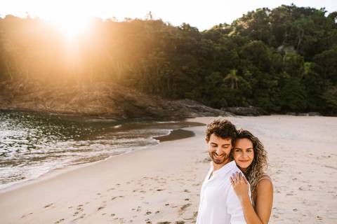     Momento espontâneo do casal caminhando pela areia ao entardecer.'