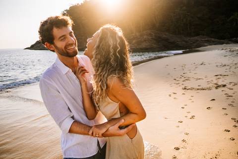    Casal sorrindo enquanto aproveita o pôr do sol em Maresias'