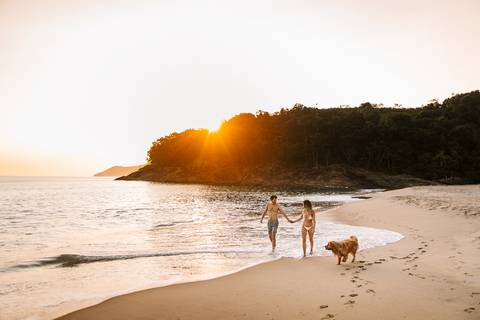     Casal caminhando pela praia durante o pôr do sol'