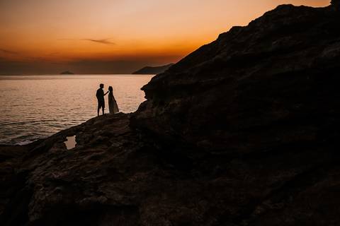     Silhueta dos noivos sobre as pedras ao pôr do sol'