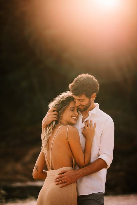     Retrato romântico do casal ao pôr do sol no litoral de São Paulo.'