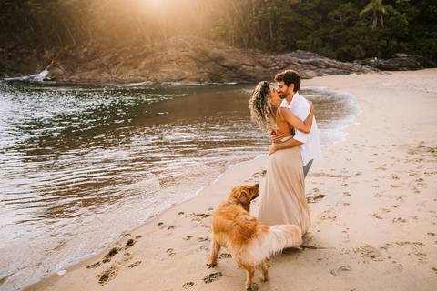     Casal caminhando com o cachorro durante ensaio pré casamento na praia.'