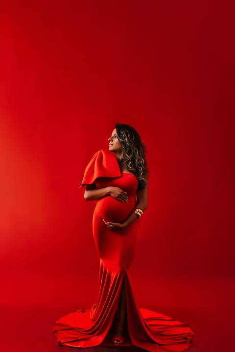     retrato gestante com vestido vermelho e fundo vermelho em estúdio'