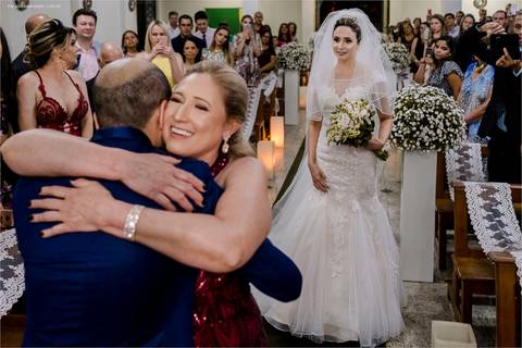 Noivo e sogra se abraçam durante a entrada da noiva, num casamento de Tarde na igreja de minas gerais. '
