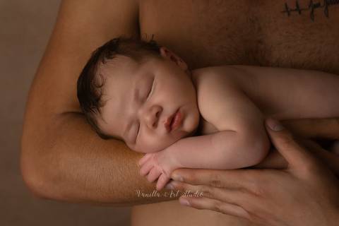 baby sleeping on daddy's arms '
