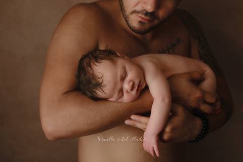 baby resting on daddy's arms '