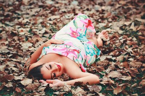 linda gestante deitada no chão com folhas secas, no Parque dos Ipes, em Santa Bárbara d'Oeste - SP'
