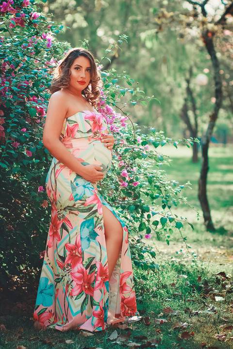 linda gestante com as mãos na barriga e fundo florido, 
'