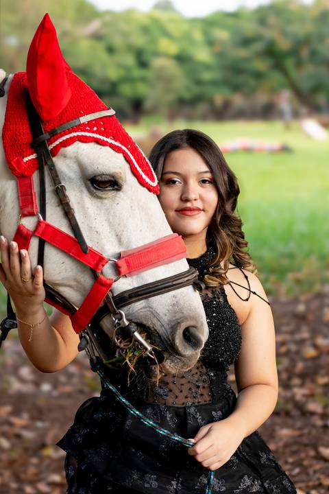Isa, em seu ensaio de 15 anos em Ribeirão Preto, demonstra toda sua paixão e carinho pelo cavalo que marcou este momento especial. O close revela a conexão única entre os dois, com destaque para o vestido preto elegante e a delicadeza do toque, mostrando '
