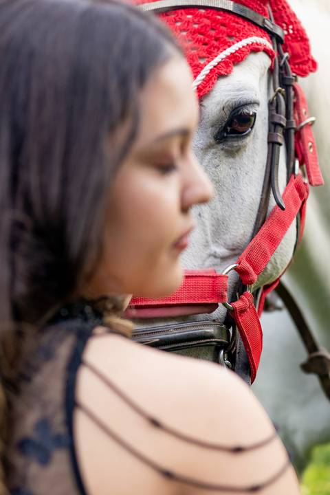 Isa, em seu ensaio de 15 anos em Ribeirão Preto, demonstra toda sua paixão e carinho pelo cavalo que marcou este momento especial. O close revela a conexão única entre os dois, com destaque para o vestido preto elegante e a delicadeza do toque, mostrando '