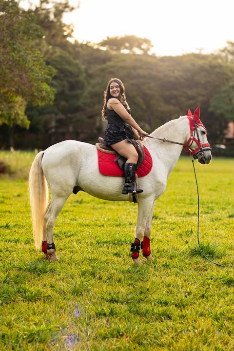 Isa, em seu ensaio de 15 anos em Ribeirão Preto, demonstra toda sua paixão e carinho pelo cavalo que marcou este momento especial. O close revela a conexão única entre os dois, com destaque para o vestido preto elegante e a delicadeza do toque, mostrando '