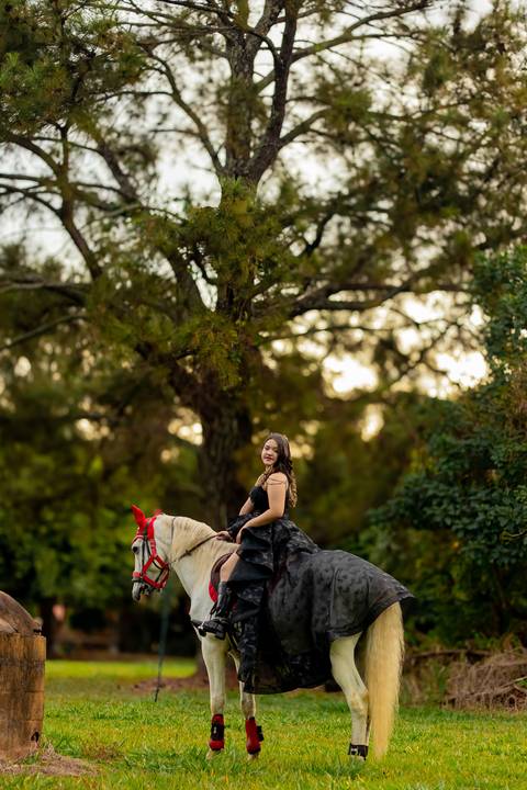 Isa, em seu ensaio de 15 anos em Ribeirão Preto, demonstra toda sua paixão e carinho pelo cavalo que marcou este momento especial. O close revela a conexão única entre os dois, com destaque para o vestido preto elegante e a delicadeza do toque, mostrando '