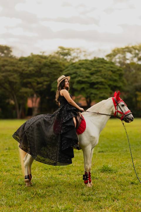 Isa, em seu ensaio de 15 anos em Ribeirão Preto, demonstra toda sua paixão e carinho pelo cavalo que marcou este momento especial. O close revela a conexão única entre os dois, com destaque para o vestido preto elegante e a delicadeza do toque, mostrando '