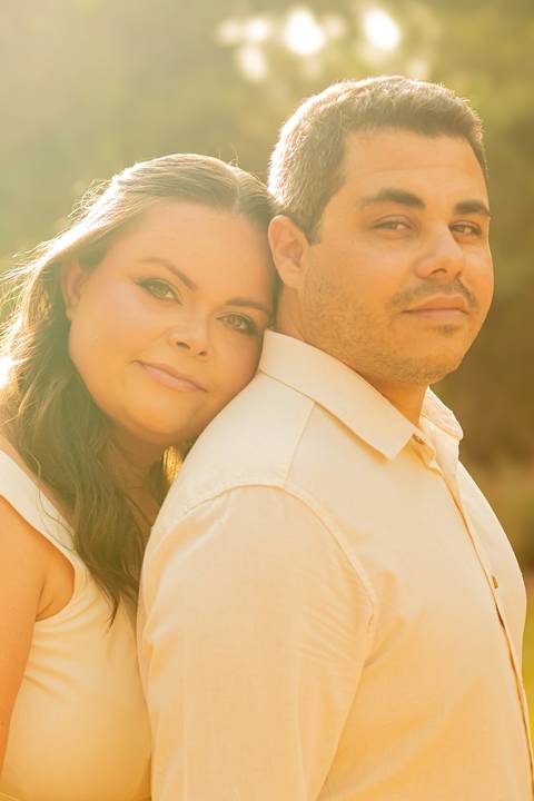 Fotógrafo de casamento em Ribeirão Preto captura Thays e Lucas abraçando o filho com risos, um retrato de família em preto e branco.'