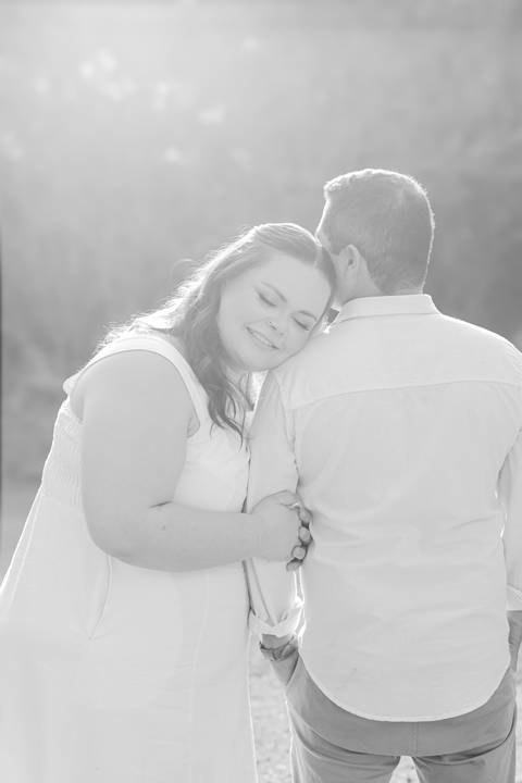 Fotógrafo de casamento em Ribeirão Preto captura Thays e Lucas abraçando o filho com risos, um retrato de família em preto e branco.'