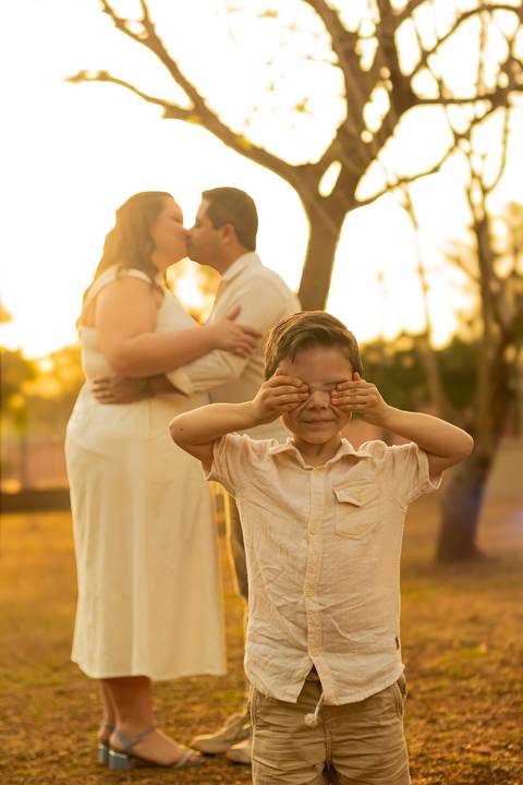 Fotógrafo de casamento em Ribeirão Preto captura Thays e Lucas abraçando o filho com risos, um retrato de família em preto e branco.'