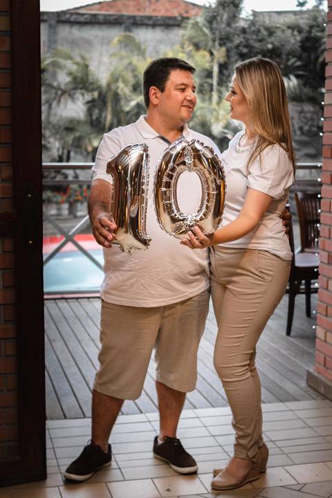 Casal segurando balão nº 10 simbolizando 10 anos de casados'