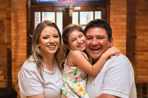 pai , mãe e filha abraçados e sorrindo'