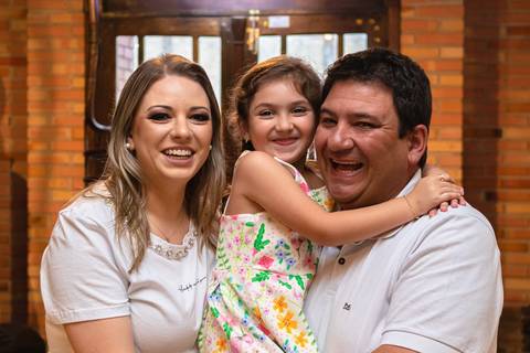 pai , mãe e filha abraçados e sorrindo'