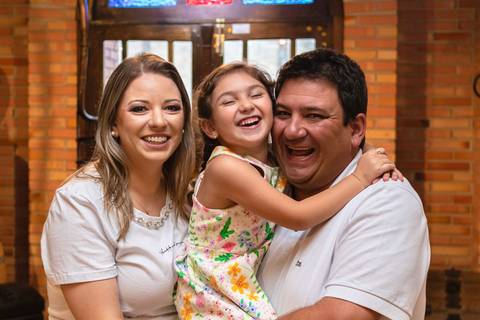 pai , mãe e filha abraçados e sorrindo'