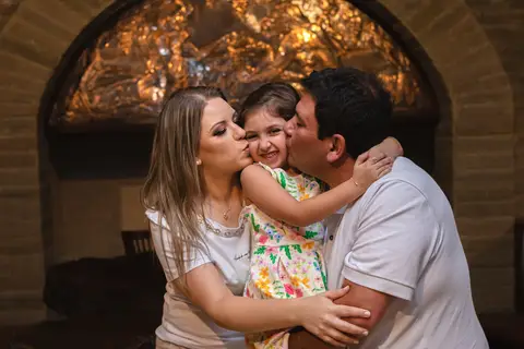 pai , mãe e filha abraçados e e dando beijo'
