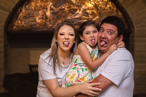 pai , mãe e filha abraçados e fazendo careta'