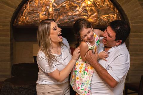 pai , mãe e filha abraçados e fazendo cosquinha'