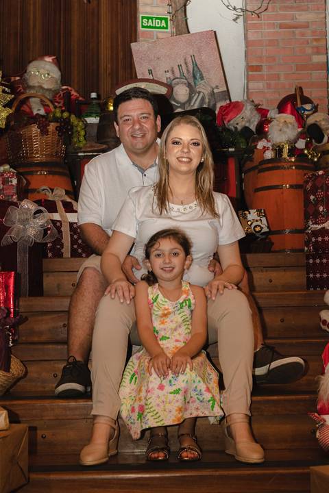 pai, mãe e filha abraçados e sentados na escada'