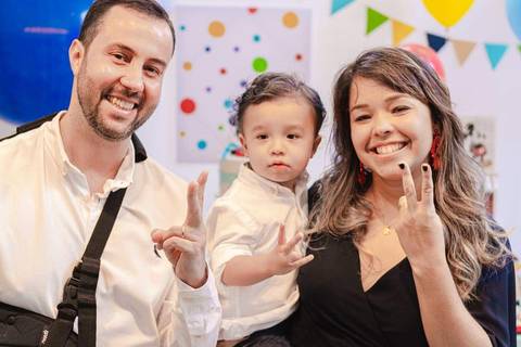 pai, mãe e filho na festa de aniversário fazendo 2 anos com os dedos '