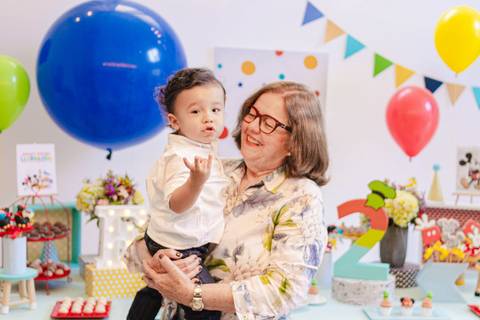 menino e avó  na festa de aniversário fazendo 2 anos com os dedos '