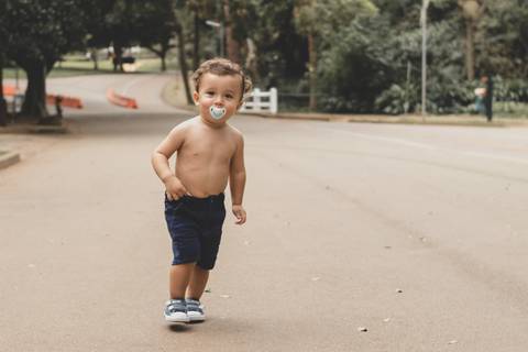 menino sem camisa correndo no parque '