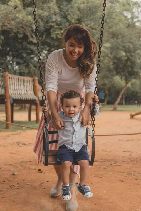 mãe brincando com filho no balanço do parquinho'