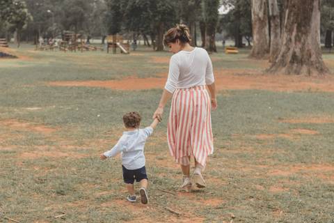 mãe caminhando no parque de mão dada com o filho'