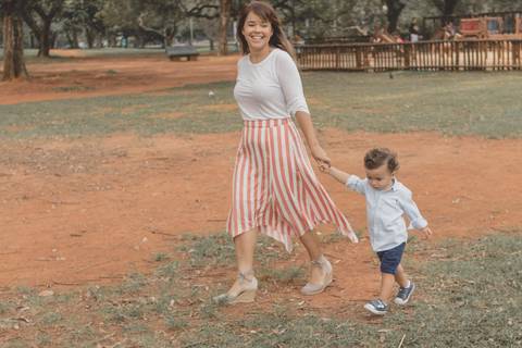 mãe correndo  de mão dada com o filho no parque'