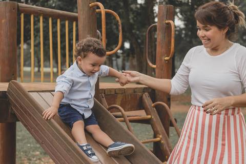 mãe brincando no  parquinho  com o filho '