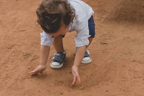 menino brincando na terra do parquinho'
