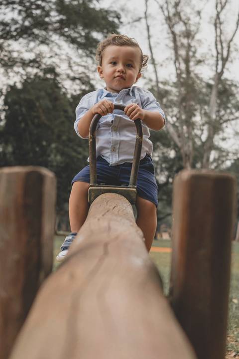 menino brincando  na gangorra no parquinho'