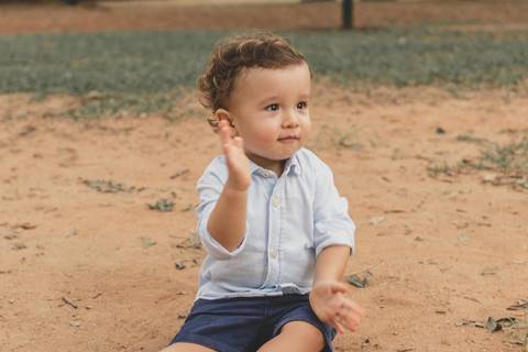menino brincando na areia do parquinho'